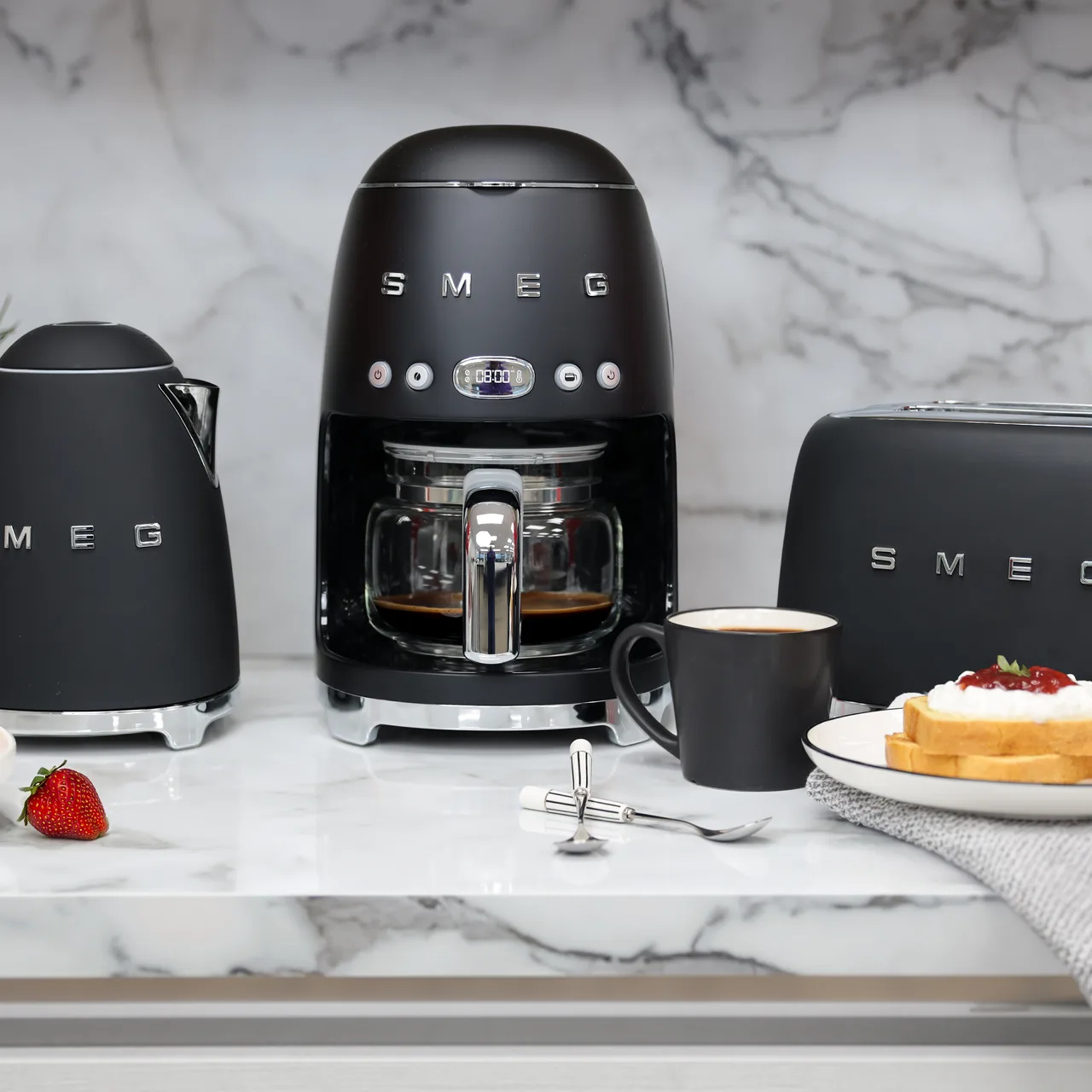 Svart vattenkokare, kaffebryggare och brödrost från Smeg på marmorbänk